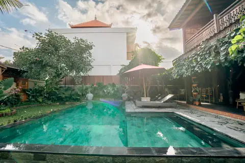 Rumah Elfi: pool with the house and a red parasol
